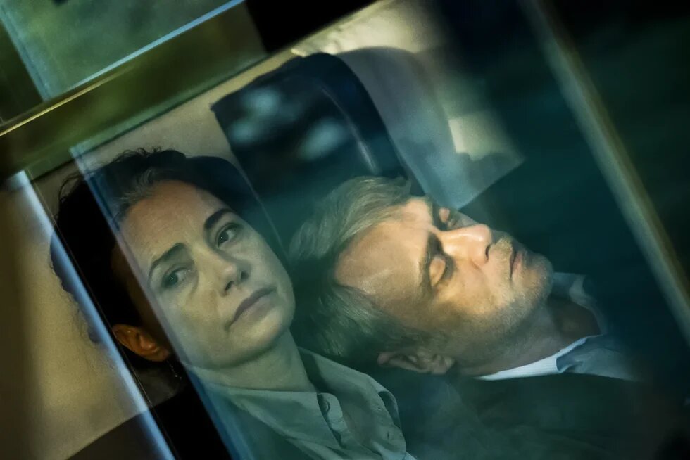 Yan yana duran ve pencereden bakan iki karakterin yer aldığı film sahnesi 